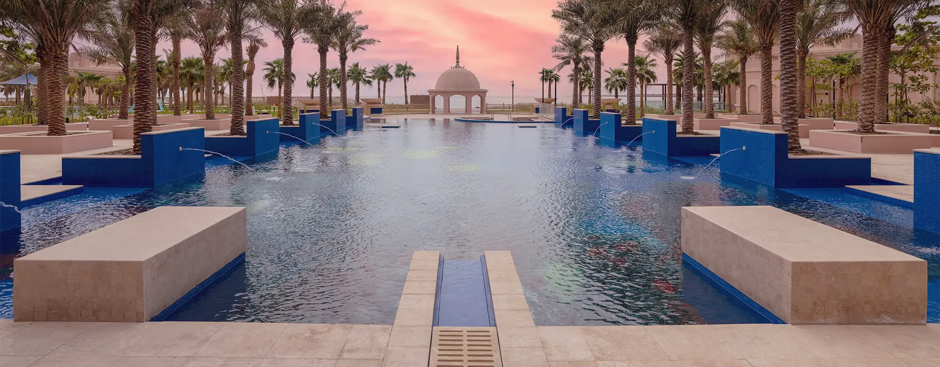 Resort pool lined with blue glass mosaic tile at sunset